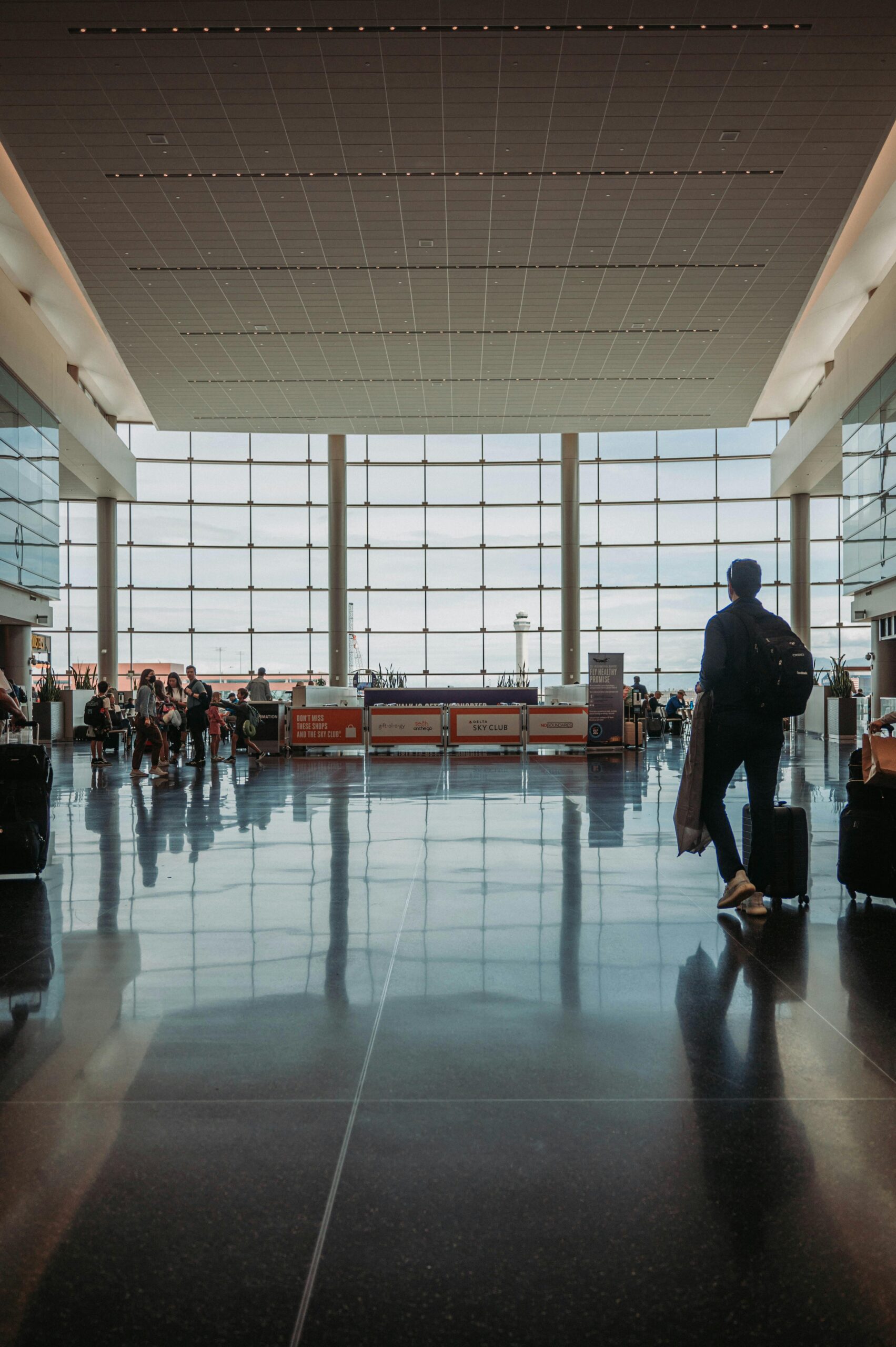 Busy airport terminal with travelers, luggage, and modern architecture.